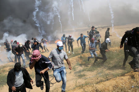 Palestinian demonstrators run for cover from tear gas fired by Israeli troops during clashes at a protest demanding the right to return to their homeland, at the Israel-Gaza border in the southern Gaza Strip, April 27, 2018. REUTERS/Ibraheem Abu Mustafa