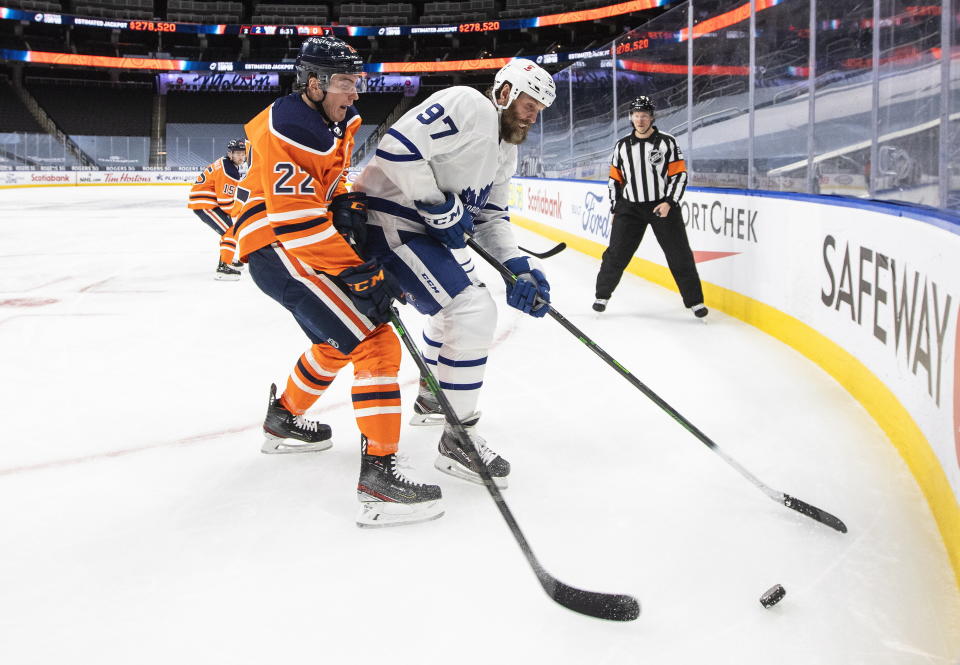 Edmonton Oilers' Tyson Barrie (22) and Toronto Maple Leafs' Joe Thornton (97) battle for the puck during first-period NHL hockey game action in Edmonton, Alberta, Monday, March 1, 2021. (Jason Franson/The Canadian Press via AP)