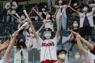 Fans wearing face masks to help protect against the spread of the new coronavirus cheer during the KBO league game between Doosan Bears and LG Twins in Seoul, South Korea, Sunday, July 27, 2020. Masked fans hopped, sang and shouted cheering slogans in baseball stadiums in South Korea on Sunday as authorities began bringing back spectators in professional sports games amid the coronavirus pandemic. (AP Photo/Ahn Young-joon)