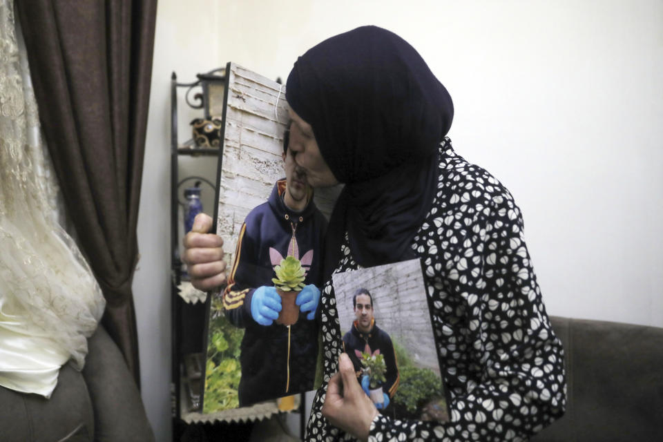 In this Wednesday, June 3, 2020 photo, Rana, mother of Eyad Hallaq, kisses his photo in their home in East Jerusalem's Wadi Joz. Early Saturday, Hallaq, a 32-year-old Palestinian with severe autism, was chased by Israeli border police forces into a nook in Jerusalem's Old City and fatally shot as he cowered next to a garbage bin after apparently being mistaken as an attacker. He was just a few meters from his beloved Elwyn El Quds school. (AP Photo/Mahmoud Illean)