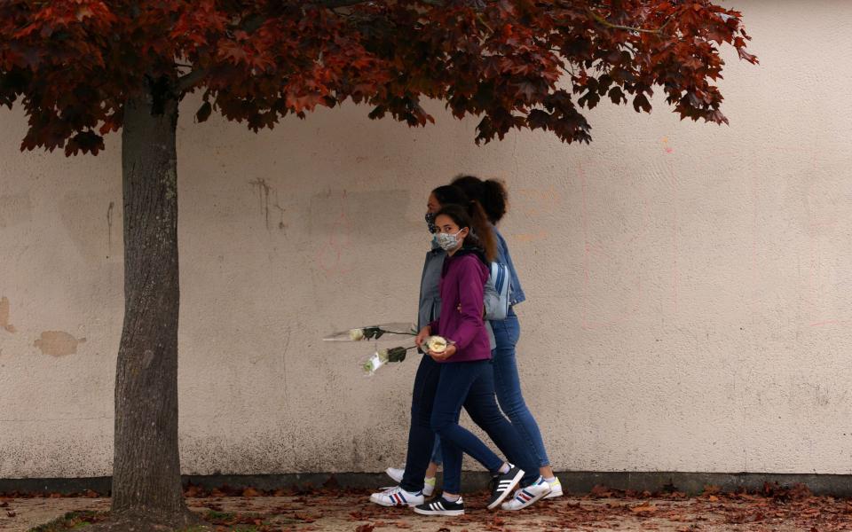 Teenagers arrive to lay flowers in front of Bois d'Aulne middle school