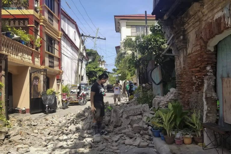 In this photo provided by the Bureau of Fire Protection, a man stands beside a damaged house after a strong earthquake struck Vigan, Ilocos Sur province, Philippines on Wednesday July 27, 2022. A strong earthquake shook the northern Philippines on Wednesday, causing some damage and prompting people to flee buildings in the capital. (Bureau of Fire Protection via AP