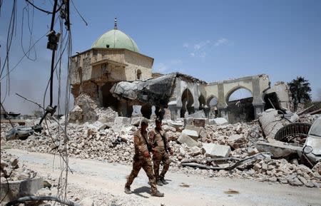 Members of Iraqi forces walk past ruined Grand al-Nuri Mosque in the Old City in Mosul, Iraq July 2, 2017. REUTERS/Erik De Castro