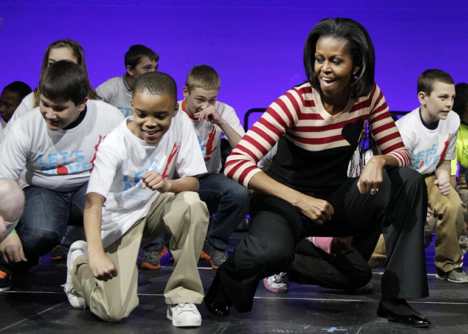 FILE - In this Feb. 9, 2012 file photo, First lady Michelle Obama does the Interlude dance with kids on stage during a Let's Move event with children from Iowa schools, at the Wells Fargo Arena in De Moines, Iowa, during her three day national tour celebrating the second anniversary of Let's Move. Nearing a milestone birthday, Michelle Obama describes herself as “50 and fabulous.” She’s celebrating already and a big birthday bash is in the works. (AP Photo/Carolyn Kaster)