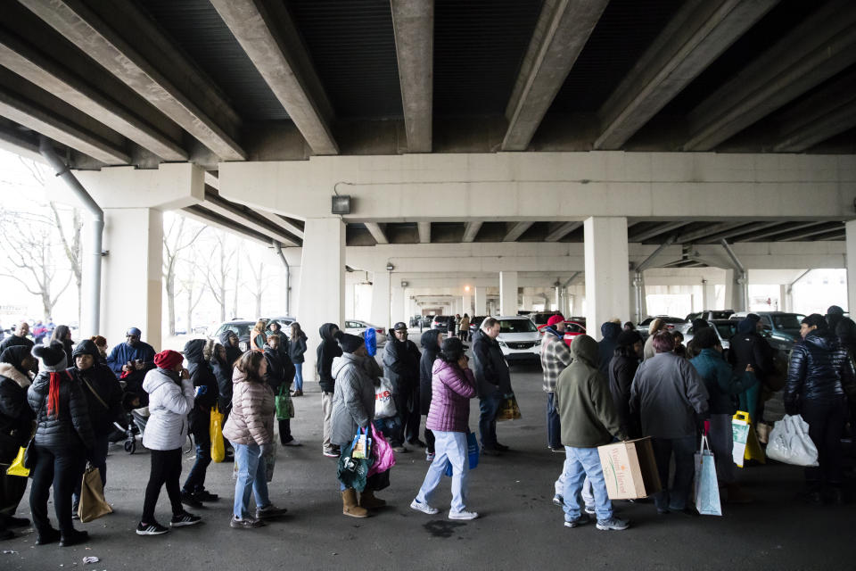 Furloughed federal workers and their families who are affected by the partial government shutdown wait in line to receive food distributed by Philabundance volunteers under Interstate 95 in Philadelphia, Wednesday, Jan. 23, 2019. (AP Photo/Matt Rourke)