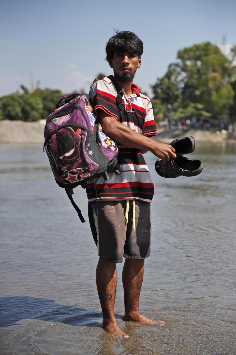 El migrante hondureño Manuel de Jesús Iraheta, posa para una foto en el río Suchiate tras regresar a la orilla Guatemala en la frontera con México, en Tecun Uman, Guatemala, el lunes 20 de enero de 2020. (AP Foto/Moisés Castillo)