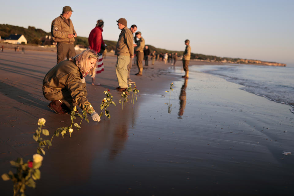 World War II reenactors put roses and flowers at dawn on Omaha Beach, in Saint-Laurent-sur-Mer, Normandy, France Monday, June 6, 2022, the day of 78th anniversary of the assault that helped bring an end to World War II. (AP Photo/Jeremias Gonzalez)