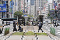 People wearing face masks make their way in Hiroshima, western Japan, Friday, May 14, 2021. Japan is set to further expand a coronavirus state of emergency, currently in Tokyo and five other prefectures, to nine areas, including HIroshima, as the government is determined to hold the Olympics in just over two months. (Shingo Nishizume/Kyodo News via AP)