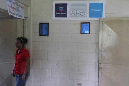 Woman stands next to a Chevron's corporate logo at the San Agustin school in La Canada de Urdaneta