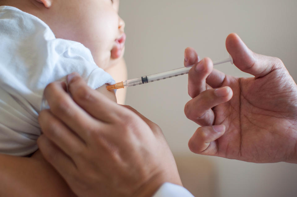 A doctor is injecting a vaccine to a baby boy indoor