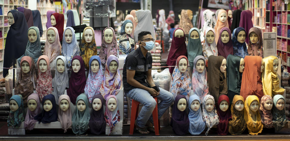 A shop vendor wearing a face mask to help curb the spread of the coronavirus waits for customers in downtown Kuala Lumpur, Malaysia, on Tuesday, Nov. 3, 2020. Malaysia extended restricted movements in its biggest city Kuala Lumpur, neighboring Selangor state and the administrative capital of Putrajaya from Wednesday in an attempt to curb a sharp rise in coronavirus cases. (AP Photo/Vincent Thian)