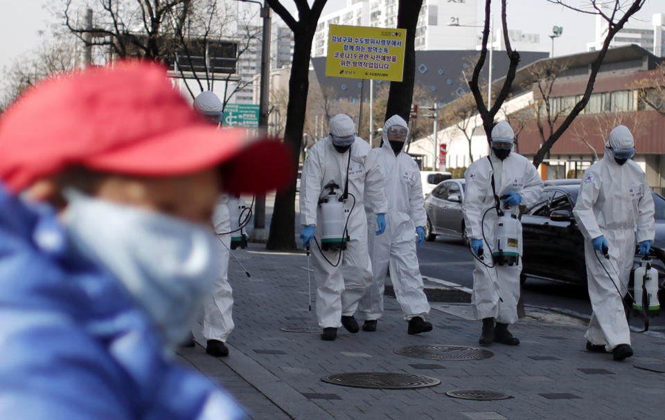 Soldados surcoreanos, con trajes de protección, esparcen desinfectante sobre una vereda dentro de los esfuerzos para luchar contra la propagación de un nuevo coronavirus, en Seúl, Corea del Sur, el 6 de marzo de 2020. (AP Foto/Lee Jin-man)