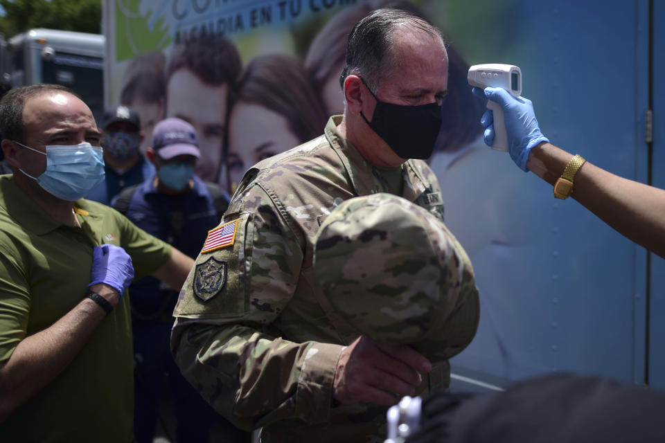 A worker measures the temperature of Gen. Jose Reyes as a precaution against the spread of the new coronavirus, as he arrives for a briefing on the aftermath of a 5.4-magnitude earthquake, in Ponce, Puerto Rico, Saturday, May 2, 2020. The quake hit near southern Puerto Rico, jolting many from their beds on an island where some people still remain in shelters from previous quakes earlier this year. (AP Photo/Carlos Giusti)