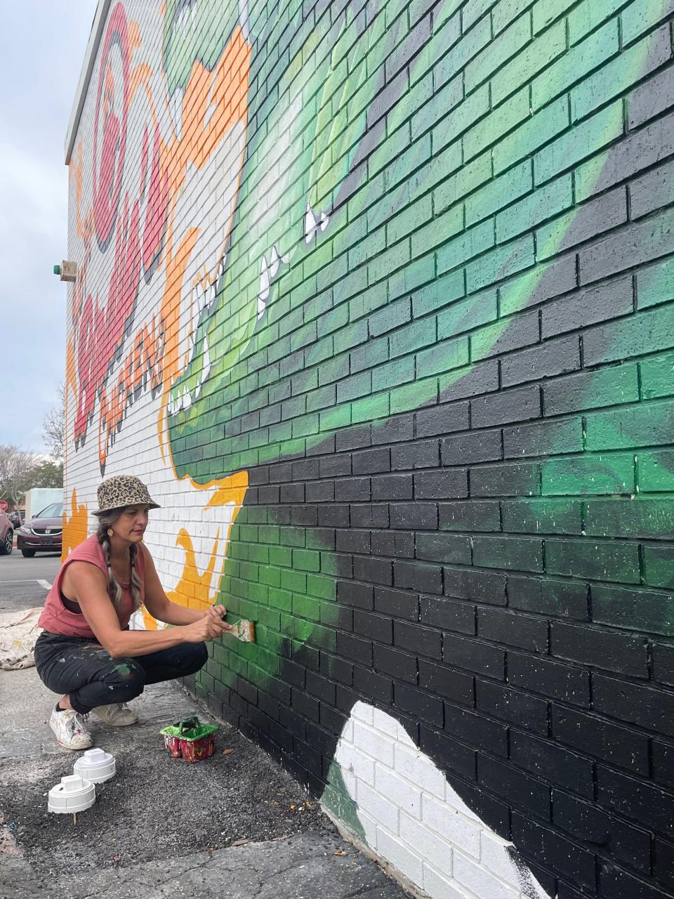 Carrie Martinez, one half the muralist team Visionary FAM, works on a mural on the side of the new Hot Birdie's Chicken restaurant on Southwest Archer Road in Gainesville.