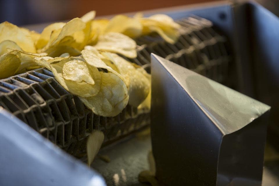 Potato chips roll off a conveyor belt after being salted Thursday, Feb. 11, 2016, on their way to packaging at Mrs. Fisher's in Rockford.