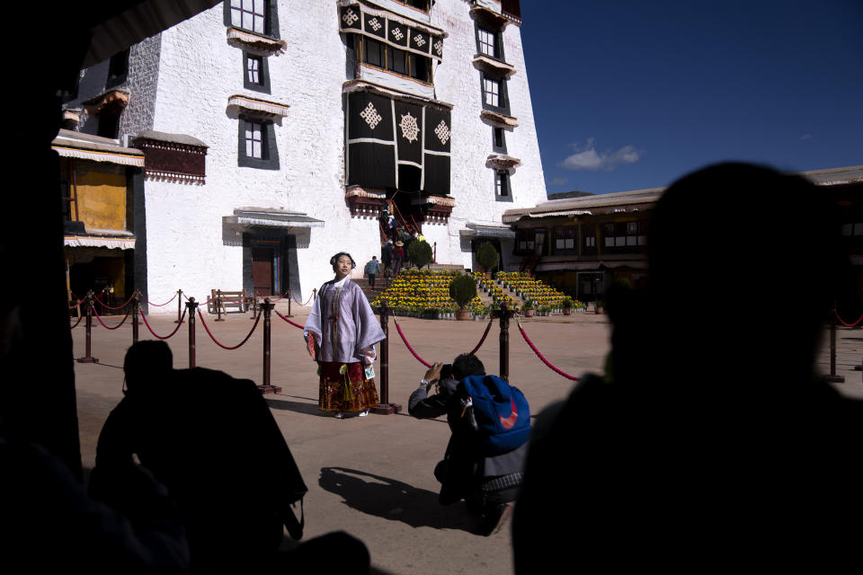 A Chinese tourist in Tibetan dress poses for a photo in a courtyard at the Potala Palace in Lhasa in western China's Tibet Autonomous Region, Tuesday, June 1, 2021. Tourism is booming in Tibet as more Chinese travel in-country because of the coronavirus pandemic, posing risks to the region's fragile environment and historic sites. (AP Photo/Mark Schiefelbein)