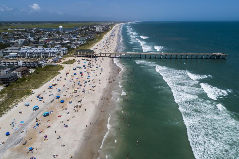 Bañistas en la playa de Wrightsville, Carolina del Norte, el domingo 2 de agosto de 2020, mientras la tormenta tropical Isaías avanza por la costa sureste del país. (Travis Long/The News & Observer via AP)