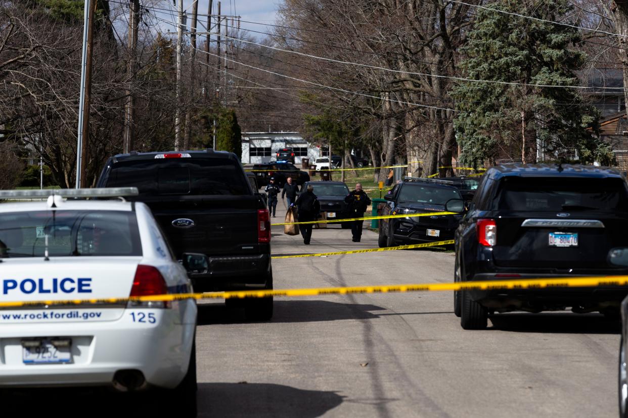 An officer carries a bag of evidence from the crime scene after multiple stabbings left four dead and seven injured on Wednesday, March 27, 2024, near Cleveland Avenue in Rockford.