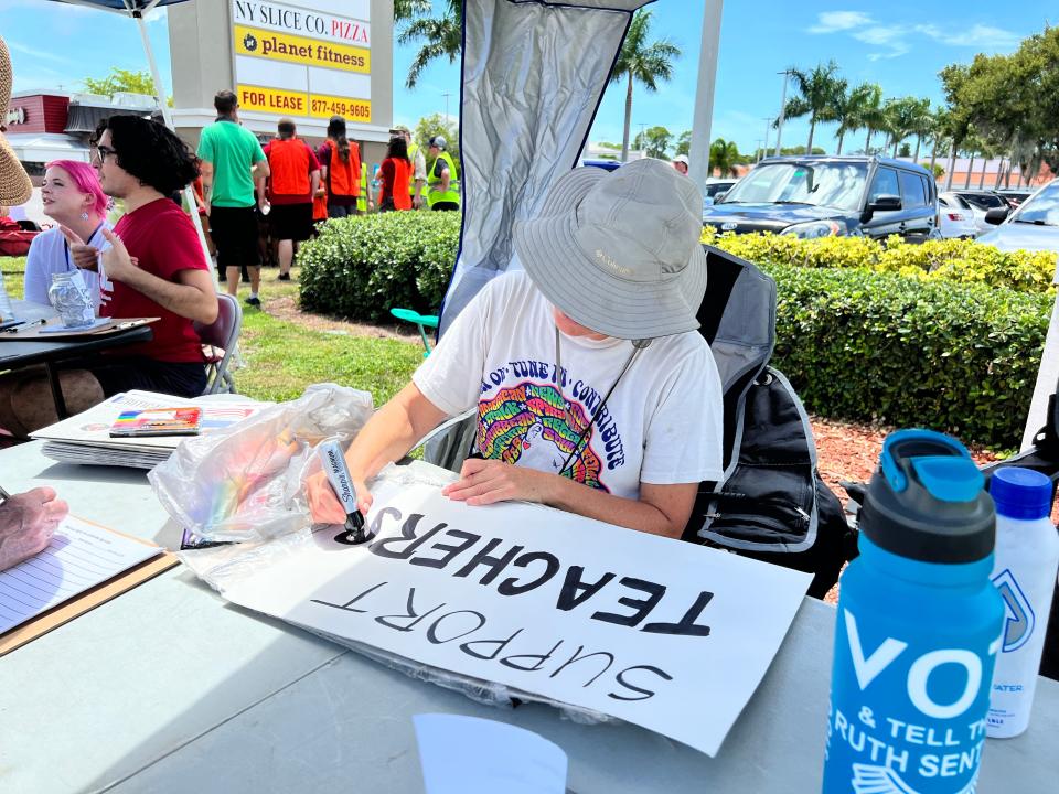 Protester draws sign reading "Support Teachers" Sunday.