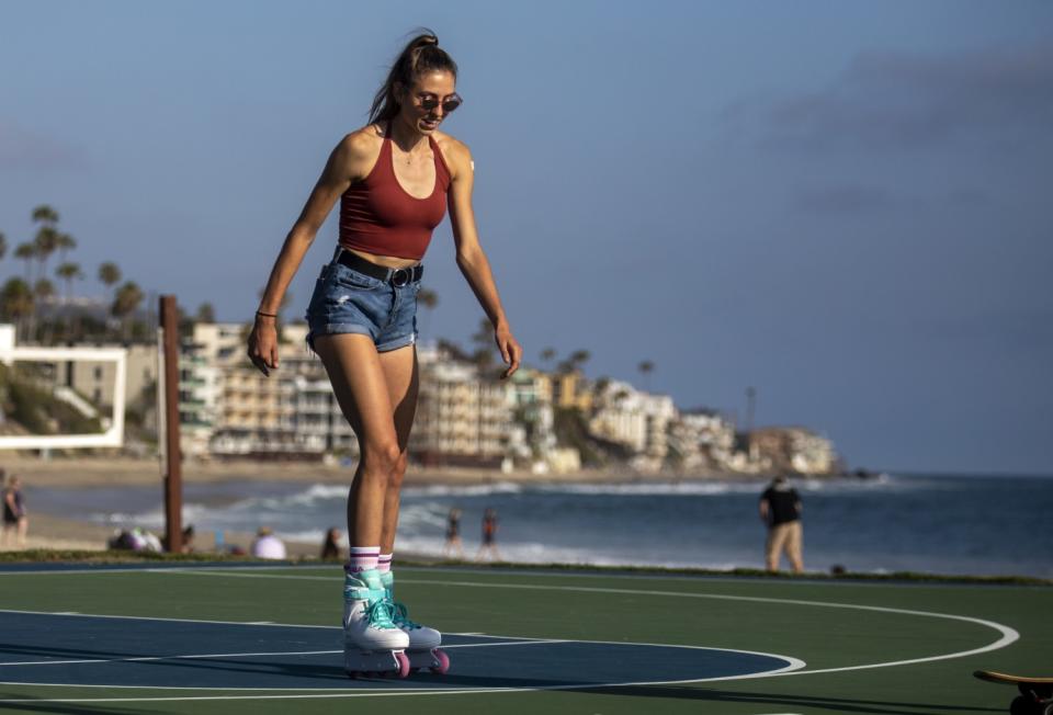 A woman roller-skates near the beach.