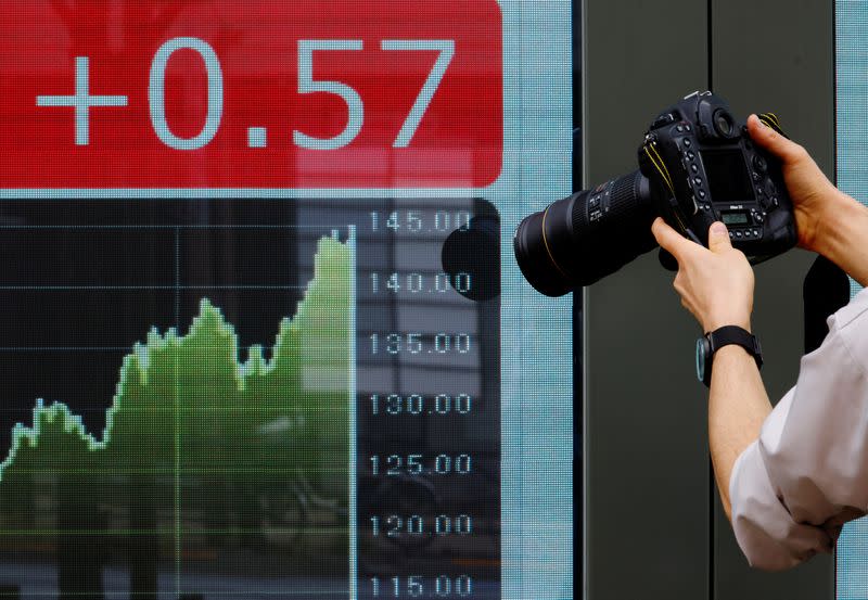 A photographer takes a photo of a board displaying a graph of the Japanese yen exchange rate against the U.S. dollar outside a brokerage in Tokyo