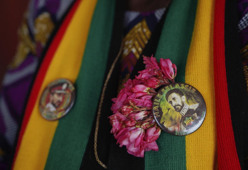 A Rastafari member wears two buttons depicting Haile Selassie I, the late Ethiopian emperor, while waiting for service to start at the Ras Freeman Foundation for the Unification of Rastafari tabernacle on Sunday, May 14, 2023, in Liberta, Antigua. Most of the Rastafari sects worship Selassie. This is rooted in Jamaican Black nationalist leader Marcus Garvey’s 1920s prediction that a “Black king shall be crowned” in Africa, ushering in a “day of deliverance.” When an Ethiopian prince named Ras Tafari, who took the name Haile Selassie I, became emperor in 1930, the descendants of slaves in Jamaica took it as proof that Garvey’s prophecy was being fulfilled. (AP Photo/Jessie Wardarski)