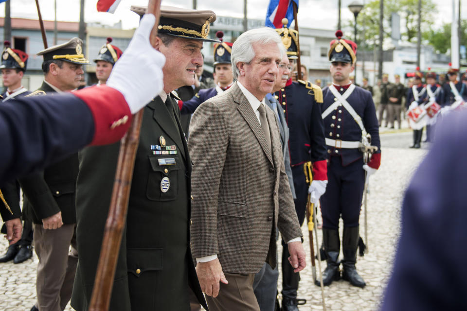 In this Oct. 29, 2018 photo, Uruguay's President Tabare Vazquez, center, walks with his commander-in-chief of the army Guido Manini Rios during a ceremony honoring independence war hero Joaquin Lencinas, also known as "Ansina," in Montevideo, Uruguay. Announced on Tuesday, March 12, 2109, Uruguay’s president has removed Manini Rios after he questioned how local courts have handled cases involving members of the military accused of crimes against humanity committed during the 1973-1985 dictatorship. (AP Photo/Matilde Campodonico)