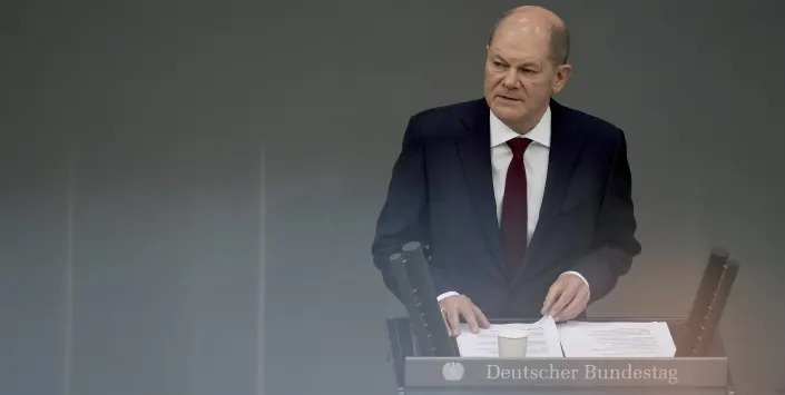 German Chancellor Olaf Scholz delivers a speech on the Russian invasion of the Ukraine during a meeting of the German federal parliament, Bundestag, at the Reichstag building in Berlin, Germany, Sunday, Feb. 27, 2022. The reflections are caused by a metallic handrail at the press tribune. (AP Photo/Michael Sohn)