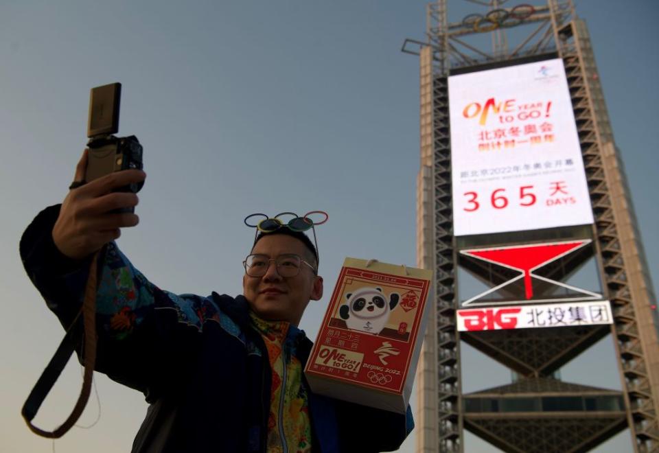 A man takes a selfie in front of a screen showing the remaining days till the 2022 Winter Olympics near the Birds Nest stadium, the venue for opening and closing ceremonies, in Beijing on February 4, 2021.<span class="copyright">NOEL CELIS/AFP via Getty Images</span>