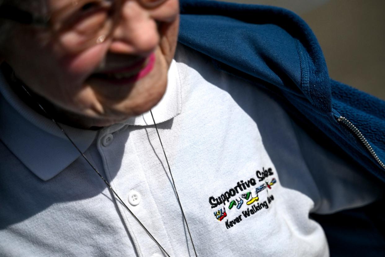 Mary Lou Lane shows off her Supportive Soles shirt on Thursday, April 25, 2024, before walking with the Living Information For Today group at the Meridian Mall in Meridian Township. Supportive Soles is one of several events that brings together those dealing with loss to offer social support.