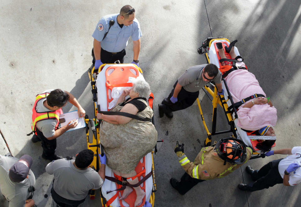 Emergency personnel attend to injured passengers after a bus accident at Miami International Airport on Saturday, Dec. 1, 2012 in Miami. Officials say a bus has hit an overpass, killing at least one person and injuring more than two-dozen people on board. Airport spokesman Greg Chin says the large, white bus hit the overpass going into the airport's arrivals section on Saturday morning. The bus was going about 20 mph when it clipped the roof entrance. (AP Photo/El Nuevo Herald, Roberto Koltun)