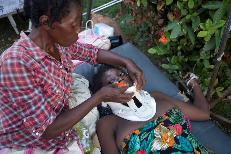 A woman lying on the floor is helped by another woman after a 7.2 magnitude earthquake in Les Cayes