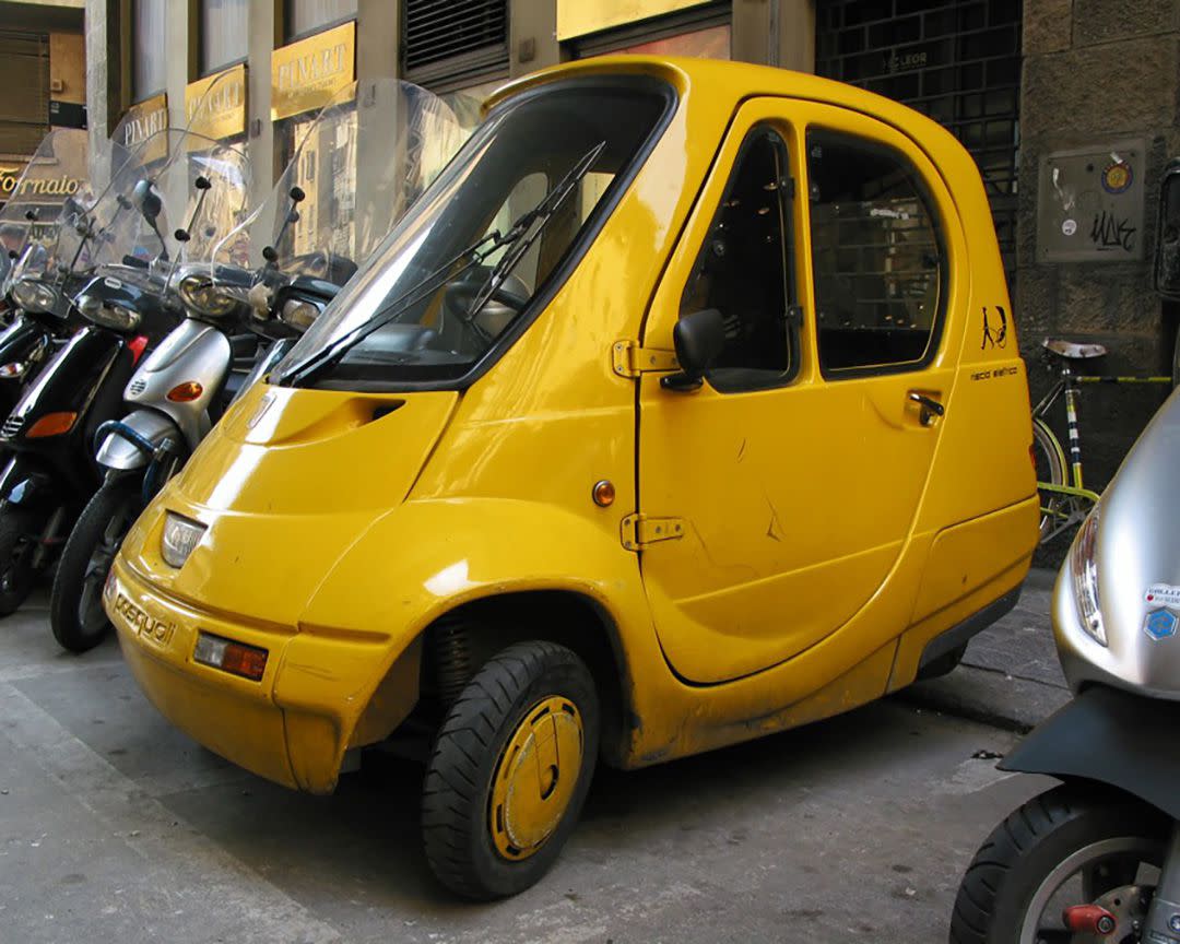 Yellow Riscio elettrico Pasquali parked between scooters on a city street