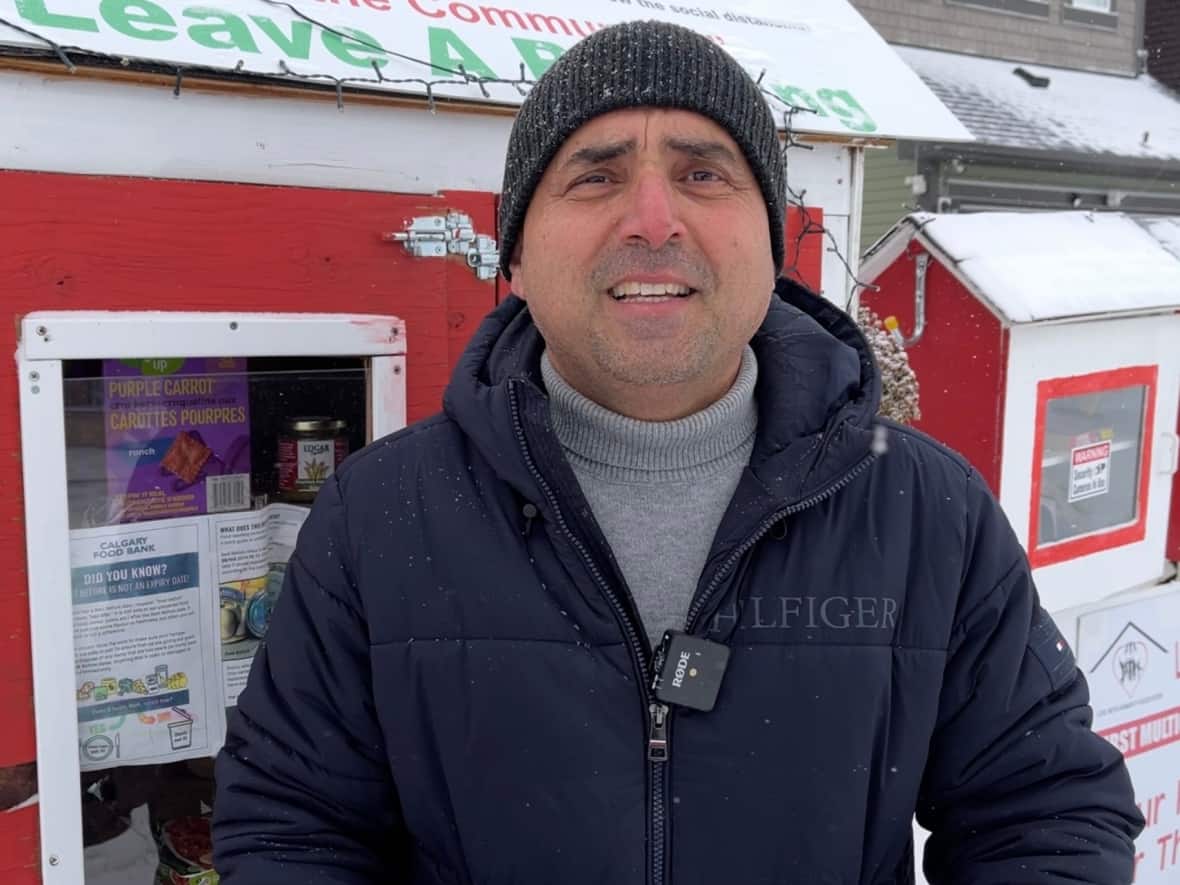 Syed Najam stands beside one of his association's eight food banks in the city. He says he’s seeing more demand than ever in the run up to Christmas this year. (Dan McGarvey/CBC - image credit)
