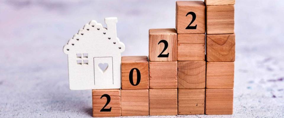 2022 housing market and property value concept with wooden cubs and small wooden house model .Mortgage rates
