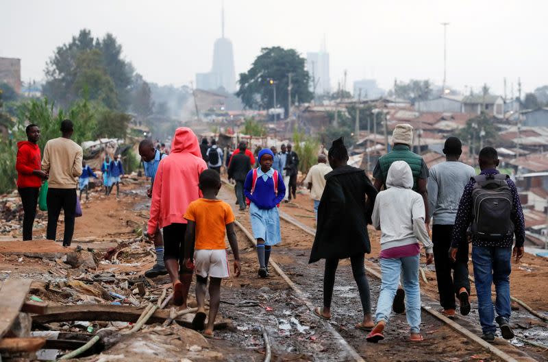 A schoolgirl walks among residents along the Kenya-Uganda railway line during the partial reopening of schools, in Nairobi