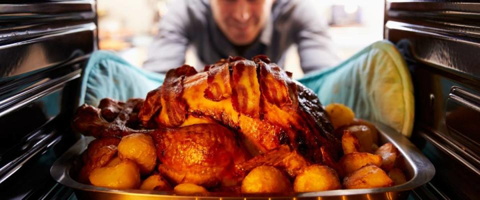 Man Taking Roast Turkey Out Of The Oven