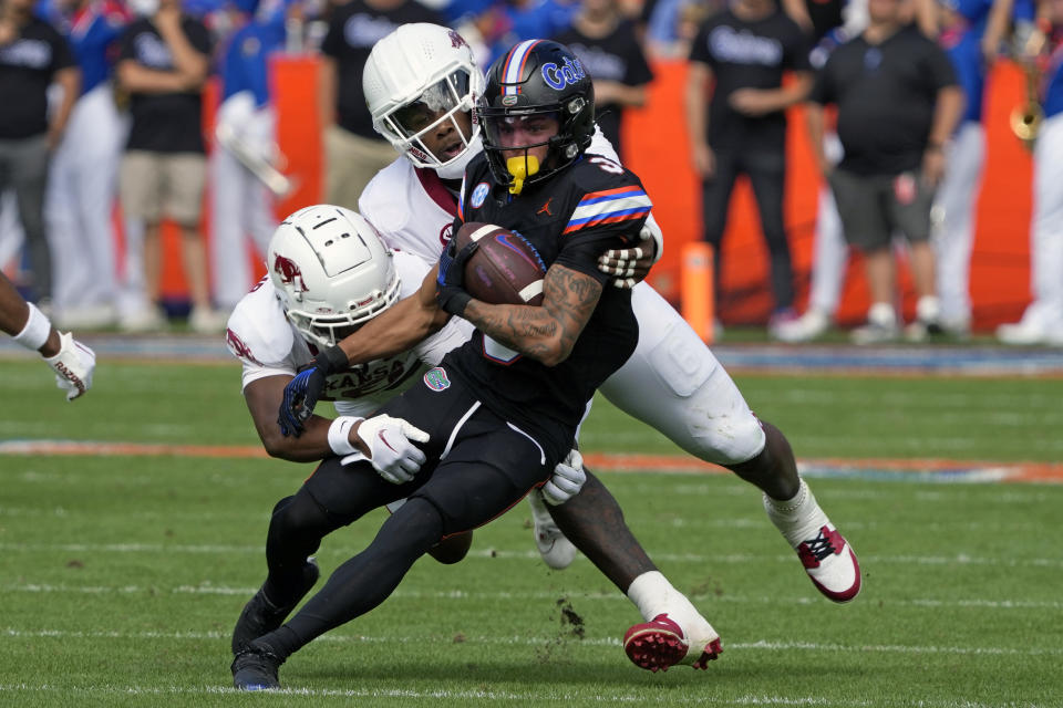 Florida wide receiver Eugene Wilson III, front right, is stopped after a reception by Arkansas defensive backs TJ Metcalf, left, and Jayden Johnson during the first half of an NCAA college football game, Saturday, Nov. 4, 2023, in Gainesville, Fla. (AP Photo/John Raoux)