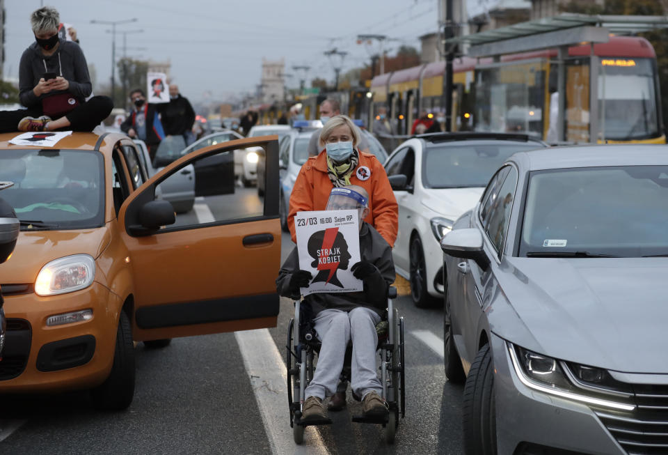 Angered women's rights activists and their supporters block rush-hour traffic at a major roundabout on the fifth day of nationwide protests against recent court ruling that tightened further Poland's restrictive abortion law, in Warsaw, Poland, on Monday, Oct. 26, 2020. The court effectively banned almost all abortions. (AP Photo/Czarek Sokolowski)