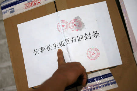 A staff from a local disease prevention and control centre points to a paper notice for recall on a sealed package of vials containing the rabies vaccines manufactured by the vaccine maker Changsheng Biotechnology in Huangshan, Anhui province, China July 23, 2018. REUTERS/Stringer