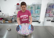 In this Tuesday, Aug. 13, 2019, photo Elizabeth Butts, owner of Sprinkle Pop, a company based in Houston that makes upscale sprinkles for bakers, mixes a batch of Unicorn sprinkles in Houston. Butts is building out and equipping a 10,000 foot facility for storage and shipping. She's reinvesting the company's profits rather than seeking investors, which will make it easier for her to run the company, but she also doesn't want to burden her company with debt. (AP Photo/David J. Phillip)