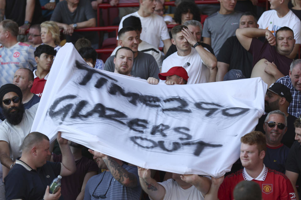 Some Manchester United fans hold up a banner protesting again not the current owners of the club ahead of the English Premier League soccer match between Brentford and Manchester United at the Gtech Community Stadium in London, Saturday, Aug. 13, 2022. (AP Photo/Ian Walton)