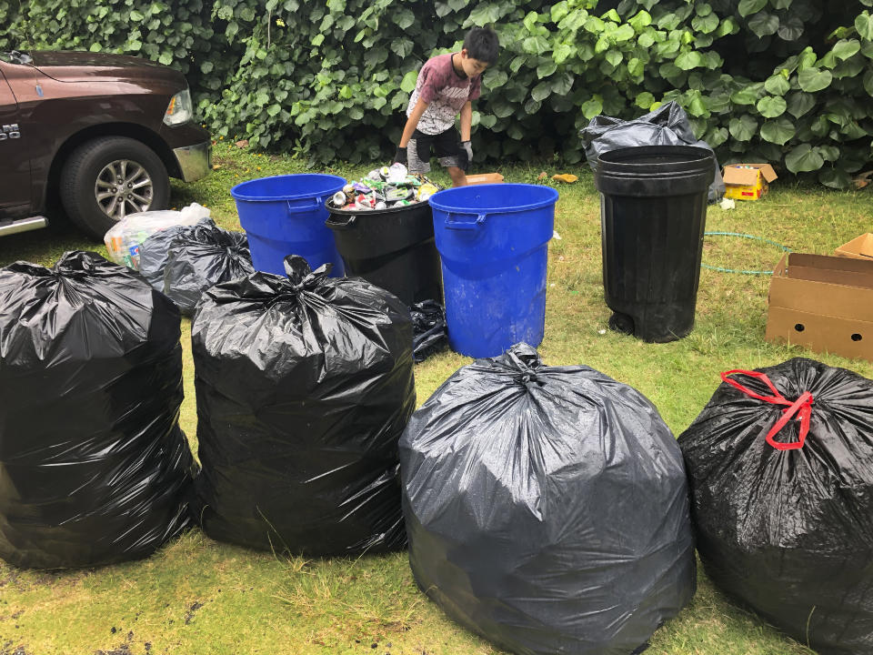 In this May 2021 photo provided by Maria Price, Genshu Price sorts recyclable cans and bottles for his fundraiser, Bottles4College, at their home in Hau'ula, Hawaii. Price started Bottles4College three years ago to raise money for his own tuition but has since expanded the recycling project to benefit other students. (Bottles4College via AP)