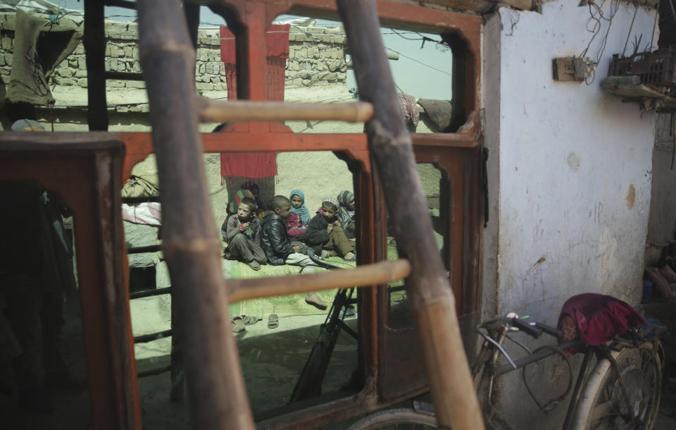 In this Sunday, March 19, 2017 photo, a children who sit in the sun are reflected in a window at their home in Kabul, Afghanistan. An aid group says nearly a third of all children in war-torn Afghanistan are unable to attend school, leaving them at increased risk of child labor, recruitment by armed groups, early marriage and other forms of exploitation. (AP Photos/Massoud Hossaini)