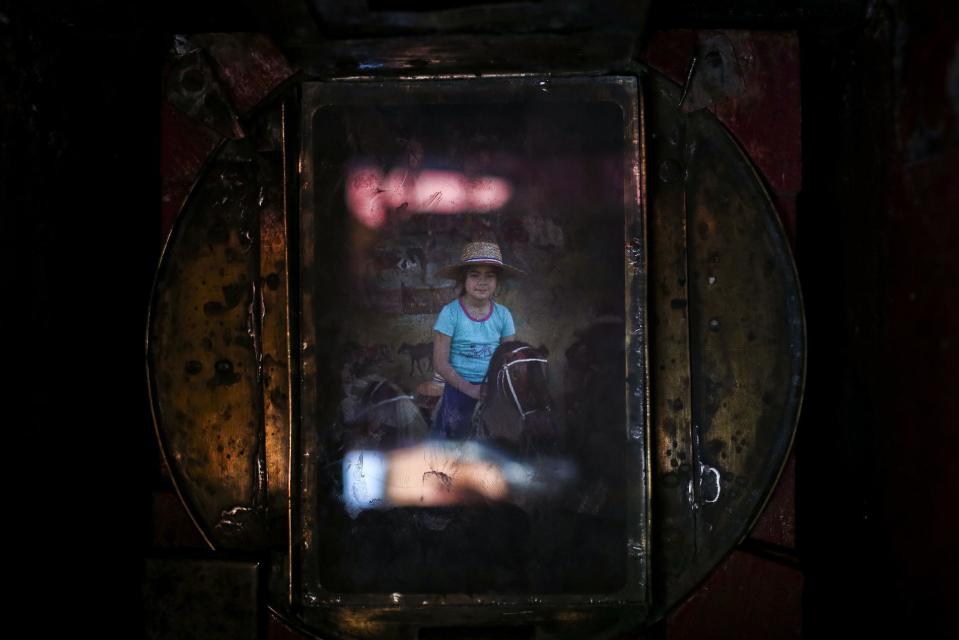 En esta fotografía del 4 de septiembre de 2016, una niña montada en un caballito de peluche aparece en el visor de la antigua cámara de caja de madera de Luis Maldonado, durante una feria por el día de la independencia en Santiago, Chile. Maldonado cree que la fotografía con ese tipo de cámara podría resucitar en Chile y quiere aumentar la concienciación sobre ese arte. (AP Foto/Esteban Félix)