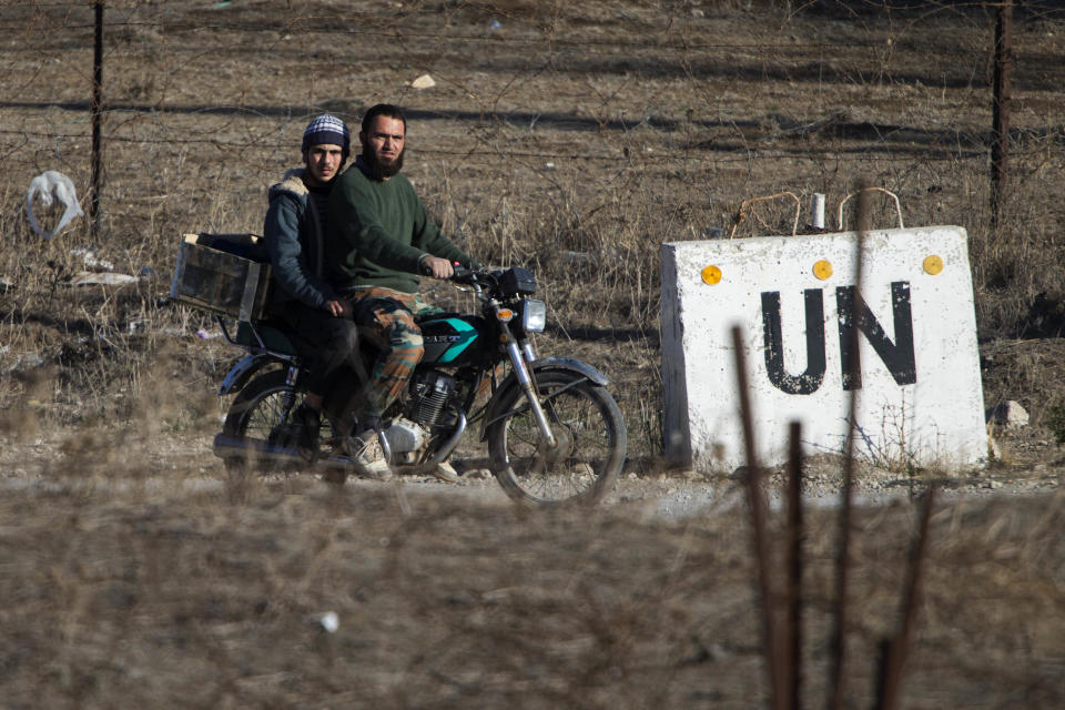 ARCHIVO - En esta fotografía de archivo de noviembre de 2016, dos hombres conducen una moticicleta hacia una base abandonada de la ONU en la frontera de Quneitra entre Siria y los Altos del Golán controlados por israelíes. (AP Foto/Ariel Schalit, Archivo)