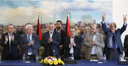 Senior Fatah official Azzam Al-Ahmed (2nd L), head of the Hamas government Ismail Haniyeh (3rd L) and senior Hamas leader Moussa Abu Marzouq (2nd R) clap after announcing a reconciliation agreement in Gaza City April 23, 2014. REUTERS/Suhaib Salem