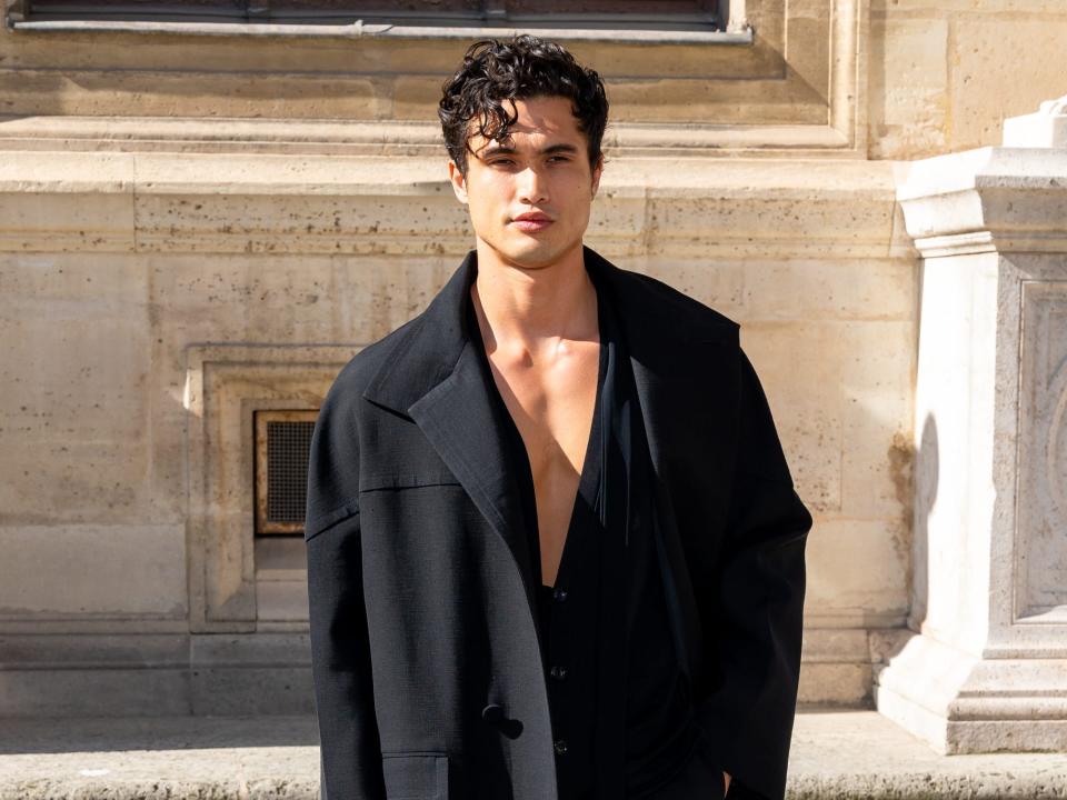 charles melton without a shirt in a long black coat