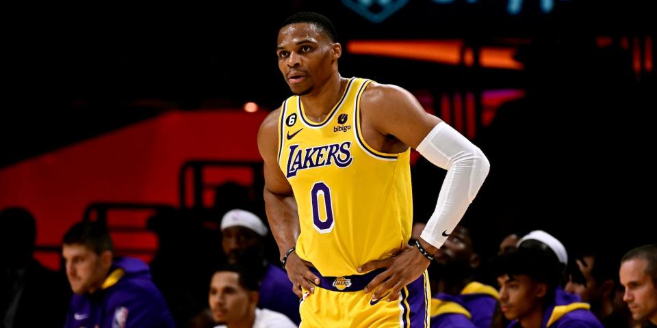 Russell Westbrook stands with his hands on his hips, with the Lakers bench in the background, during a game in 2022.