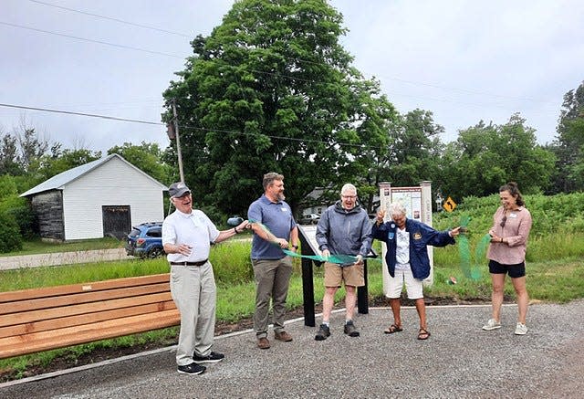 Officials and Hayes family members cut the opening ribbon on a new bench and historical sign, located in Carp Lake at the intersection of Gill Road and the North Western State Trail. Pictured (from left) are Jim Conboy, TOMTC board; Brent Bolin, TOMTC executive director; Andy Hayes, TOMTC board; Ann Hayes, niece of George Hayes; and Becca Nelson, TOMTC staff.